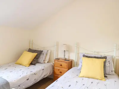 two beds sitting next to each other in a bedroom at Honeysuckle Cottage in Swaffham