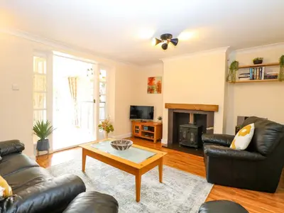 a living room with a leather couch and a coffee table at Honeysuckle Cottage in Swaffham