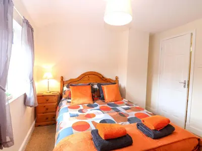 a bedroom with a bed with orange and blue pillows at Honeysuckle Cottage in Swaffham