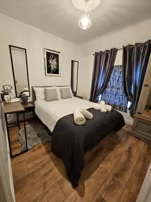 a bedroom with a large bed with a black blanket at Apartment Royston Center in Royston
