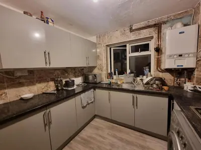 a kitchen with white cabinets and a sink and a window at Budget Room Stevenage Town Centre in Stevenage