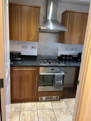 a kitchen with wooden cabinets and a stove top oven at Stunning 2BR house in Colchester in Colchester