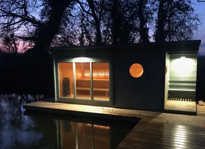 a tiny house on the water at night at Muntjac Cabin in Elmswell