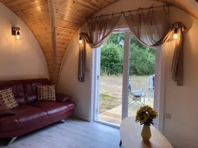 a living room with a couch and a glass door at Muntjac Cabin in Elmswell