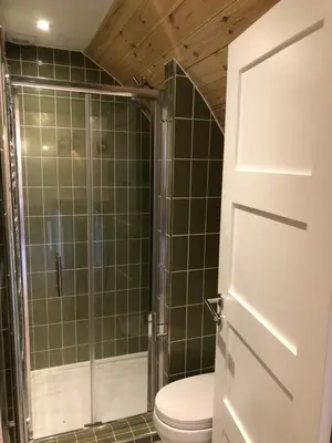 a bathroom with a toilet and a glass shower at Muntjac Cabin in Elmswell