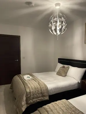 a bedroom with two beds and a chandelier at The Crimsons, with free parking, Harlow in Harlow