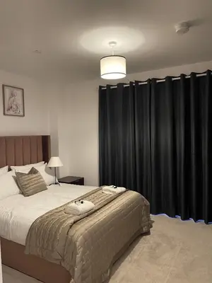 a bedroom with a large bed with black curtains at The Crimsons, with free parking, Harlow in Harlow