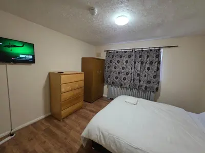 a bedroom with a bed and a tv on the wall at Spacious Double Room in Basildon Essex in Basildon