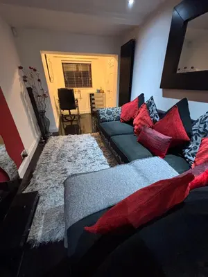 a living room with a blue couch and red pillows at Amazing studio room in a beautiful house in Stanford le Hope