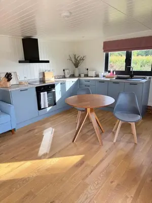 a kitchen with a wooden table and two chairs at The Den in Scoulton