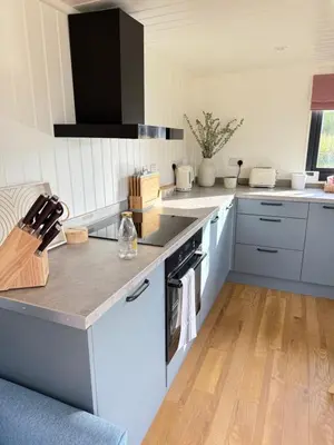 a kitchen with white cabinets and a stove top oven at The Den in Scoulton