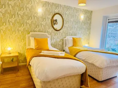 two beds in a room with yellow and green wallpaper at Spacious 2 Bedroom Sleeps 4 with WiFi & Garden in Cambridge