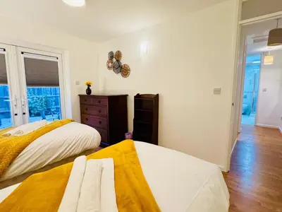 a bedroom with two beds and a dresser and a window at Spacious 2 Bedroom Sleeps 4 with WiFi & Garden in Cambridge