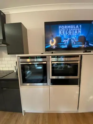 a kitchen with two ovens and a flat screen tv at Two double bedroom self contained Retreat in Thundersley