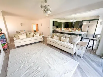 a living room with two white couches and a kitchen at Oceanfront 4BR Beach Retreat in Holland-on-Sea