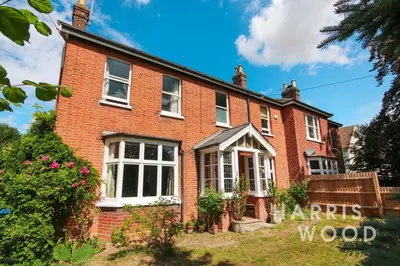 a red brick house with white windows and a fence at Beaulieu in East Bergholt