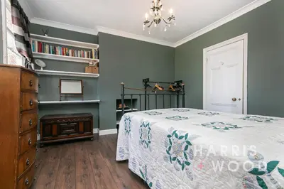 a bedroom with green walls and a bed and a dresser at Beaulieu in East Bergholt
