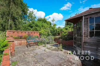a garden with a bench and a brick wall at Beaulieu in East Bergholt