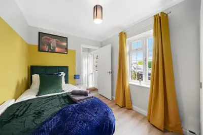 a bedroom with a bed and a window with yellow curtains at Detached 6 Bedroom Cambridgeshire Abode - Pets in Whittlesford