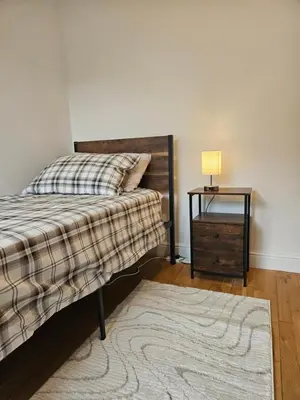 a bedroom with a bed and a table with a lamp at Gorgeous Flat with Charming Patio in Cambridge