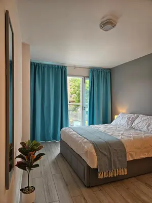 a bedroom with a bed and a window with blue curtains at Gorgeous Flat with Charming Patio in Cambridge