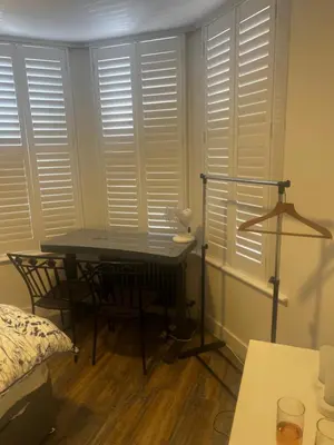 a bedroom with white shuttered windows and a desk at Southend Luxe Retreat in Southend-on-Sea