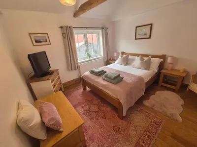 a bedroom with a bed and a television in it at Lime Kiln Quay Cottage in Woodbridge