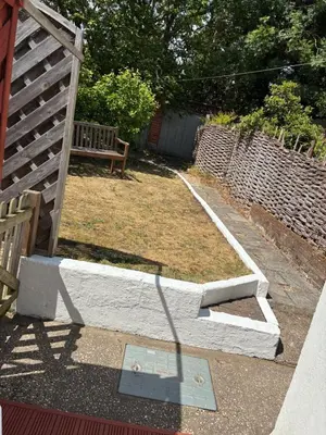 a garden with a bench and a brick wall at Lime Kiln Quay Cottage in Woodbridge