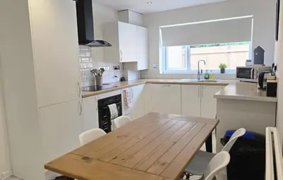 a kitchen with a wooden table and white cabinets at Grace's Place in Littleport in Littleport