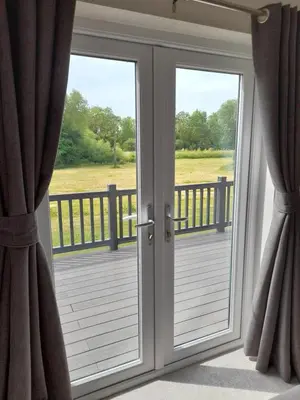 a sliding glass door with a view of a deck at Pullman Lodge in Glemsford