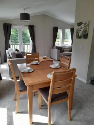 a living room with a wooden table and chairs at Pullman Lodge in Glemsford