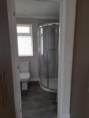 a bathroom with a glass shower and a toilet at Pullman Lodge in Glemsford