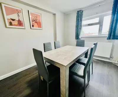 a dining room with a wooden table and chairs at Spacious 6 Bedroom House Basildon with Free Parking for Contractors and Business - Free Parking l sleeps 12 in Basildon