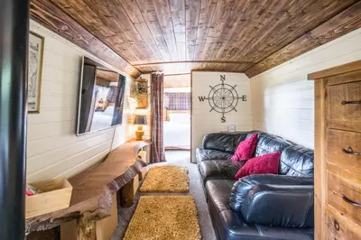 a living room in a tiny house with a leather couch at The Bus Stop, Thornham Magna in Thornham Magna