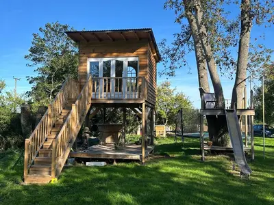 a tree house with a deck and a staircase at The Bus Stop, Thornham Magna in Thornham Magna