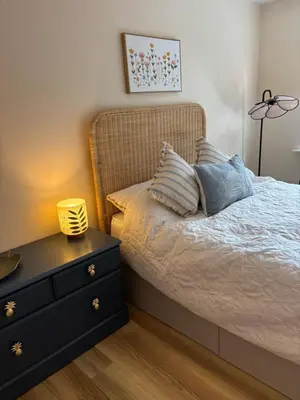 a bedroom with a bed with a nightstand and a lamp at Cosy central hideout in Ware