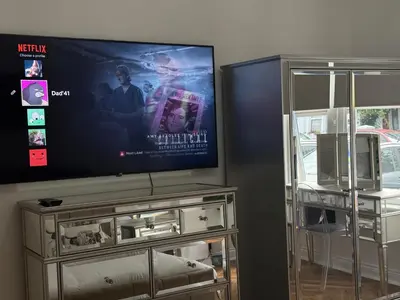 a flat screen tv sitting on top of a entertainment center at Southend Apartment With Parking, Private Garden and Beach Side Location in Southend-on-Sea