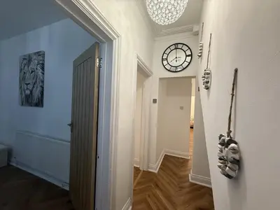a hallway with a clock on the wall and a door at Southend Apartment With Parking, Private Garden and Beach Side Location in Southend-on-Sea