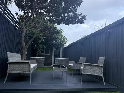 a deck with chairs and a table and a tree at Southend Apartment With Parking, Private Garden and Beach Side Location in Southend-on-Sea