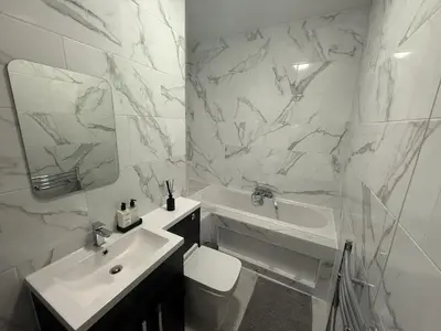 a white bathroom with a sink and a mirror at Southend Apartment With Parking, Private Garden and Beach Side Location in Southend-on-Sea