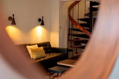 a living room with a couch and a spiral staircase at Modern and Stylish Townhouse in City Centre Pass the Keys in Cambridge