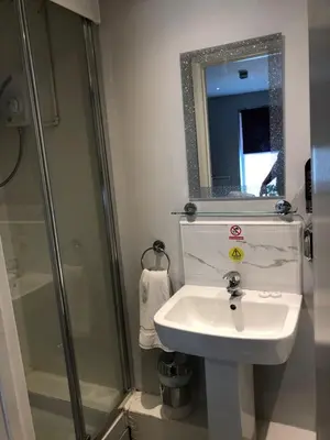 a bathroom with a sink and a shower and a mirror at OYO Watton Vibe Hotel in Watton