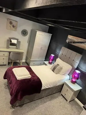 a bedroom with a large bed with purple lamps on it at OYO Watton Vibe Hotel in Watton