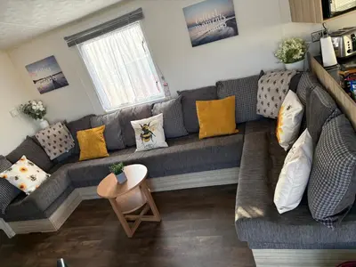 a living room with a gray couch with yellow pillows at Centrix at Seawick Holiday Park in Saint Osyth