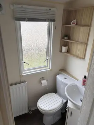 a bathroom with a toilet and a sink and a window at Centrix at Seawick Holiday Park in Saint Osyth