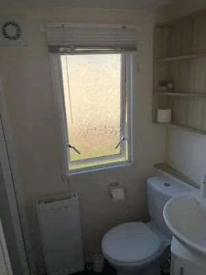a bathroom with a white toilet and a window at Centrix at Seawick Holiday Park in Saint Osyth