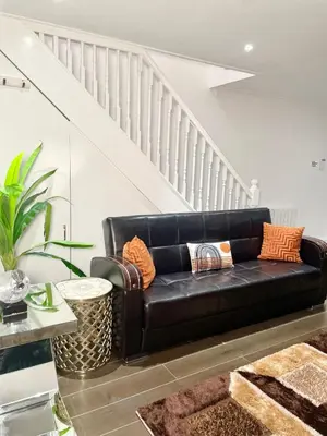 a black leather couch in a living room with a staircase at Relaxed Leigh-on-Sea Escape, Family-Friendly & Contractor Stays in Hockley