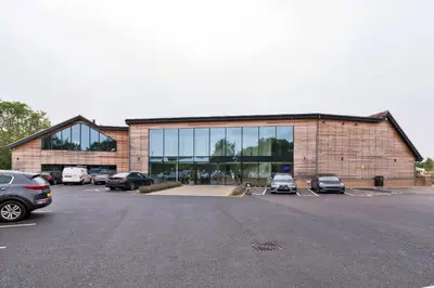 a large building with cars parked in a parking lot at Finest Retreats - Cambridge Luxury Lodge