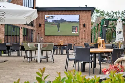 a patio with tables and chairs and a large screen at Finest Retreats - Cambridge Luxury Lodge