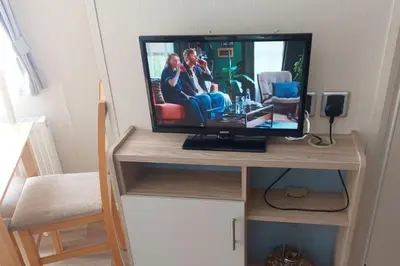a television on a wooden stand with a tv on it at Seaside Lodge Haven in St Osyth in Jaywick Sands